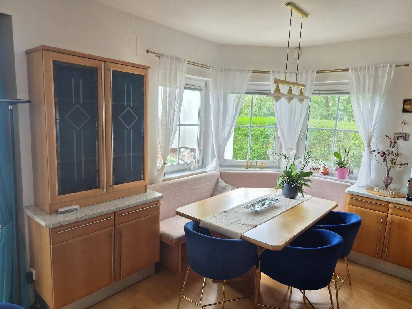 Gemütlicher Essbereich mit Eckbank, Holztisch und großen Fenstern mit Gartenblick.