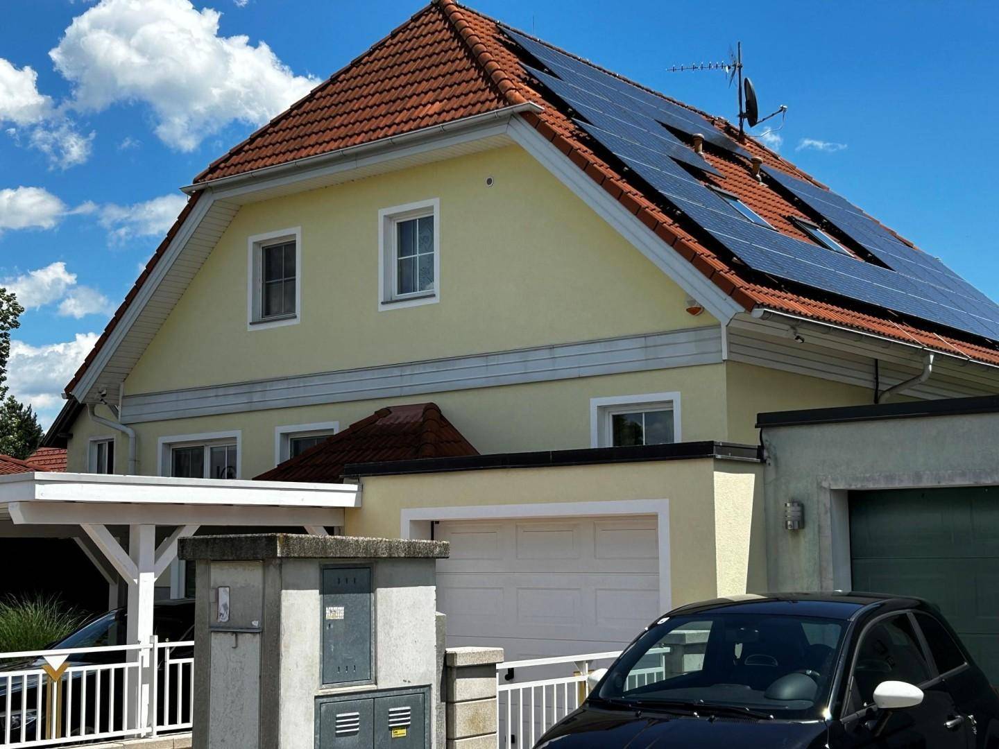 Seitenansicht des Hauses mit Photovoltaikanlage auf dem Dach und Garage.