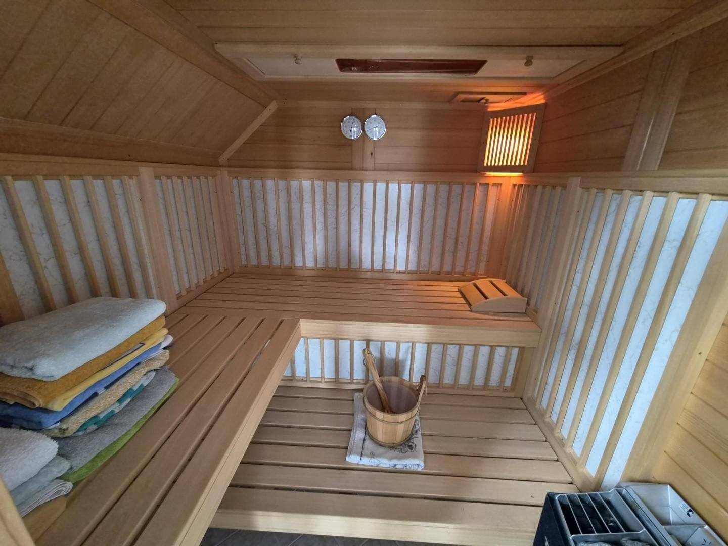 Gemütliche Holzsauna mit Bänken und traditionellem Saunaofen für Entspannung.