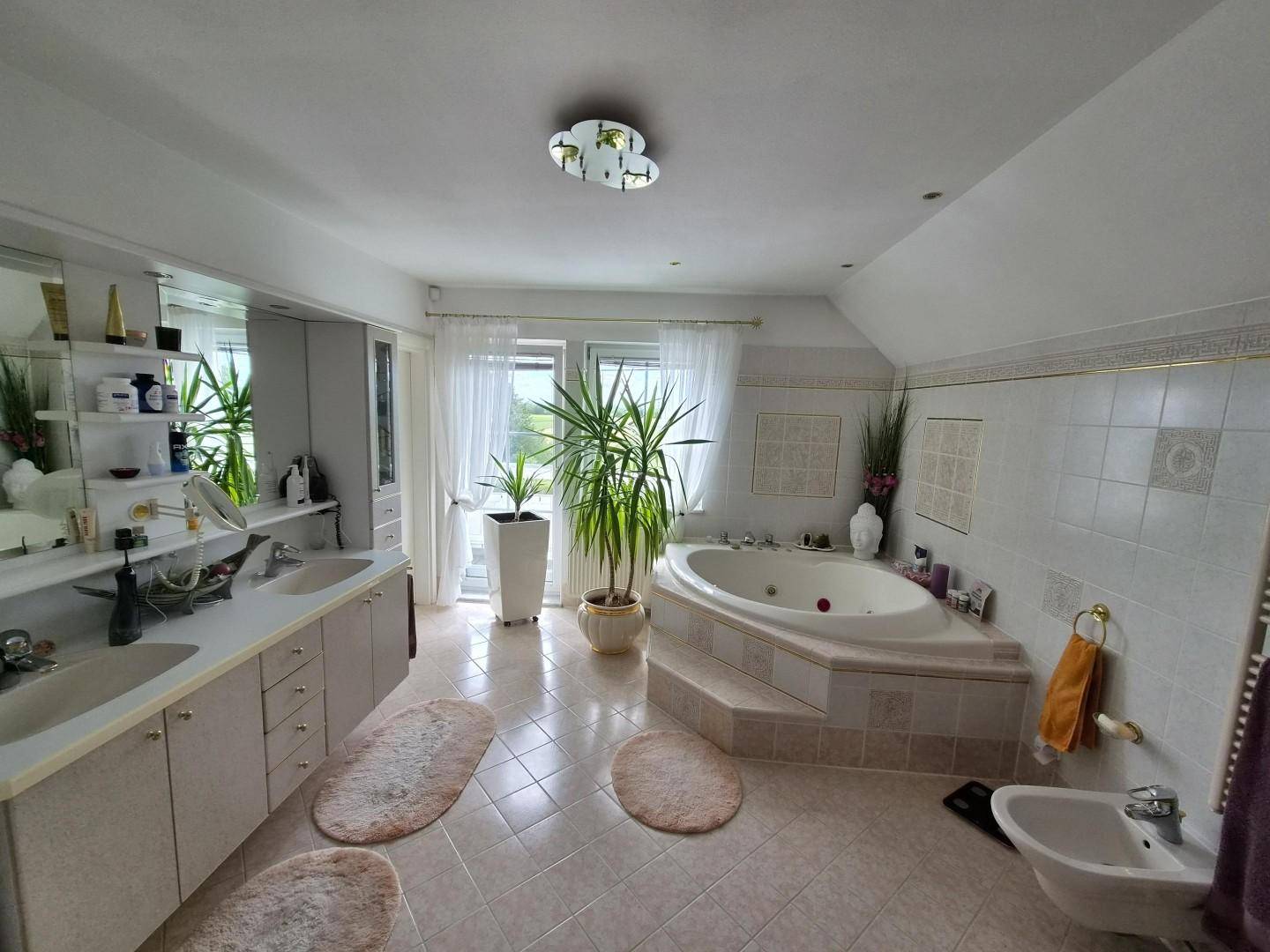 Geräumiges Badezimmer mit Eckbadewanne, Doppelwaschbecken und Bidet im Dachgeschoss.