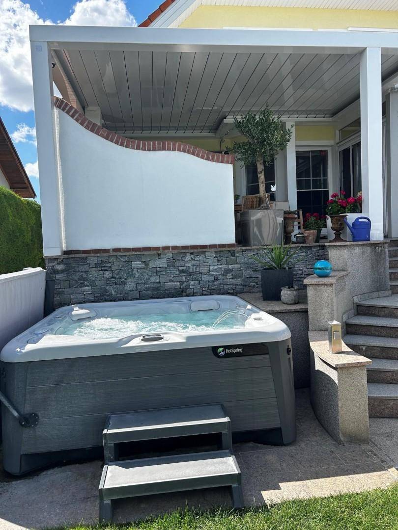 Entspannungsbereich im Freien mit Whirlpool und Zugang zur überdachten Terrasse.