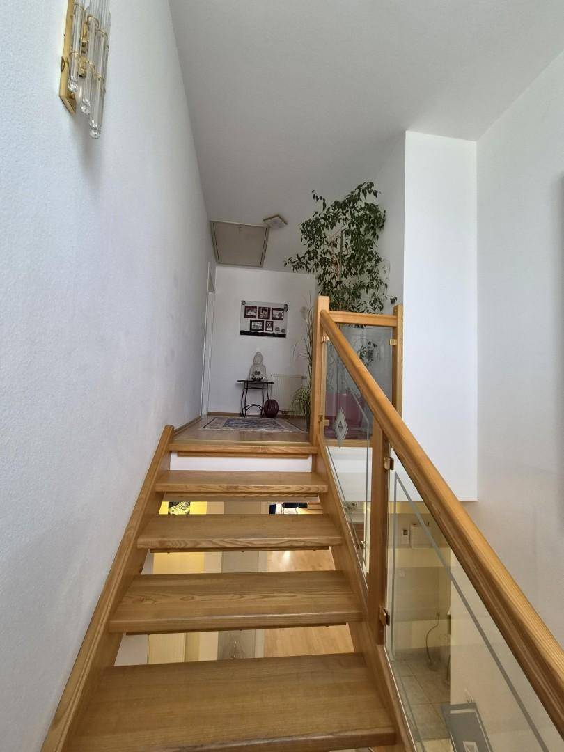 Helle Holztreppe mit Glasgeländer führt in die obere Etage des Hauses.