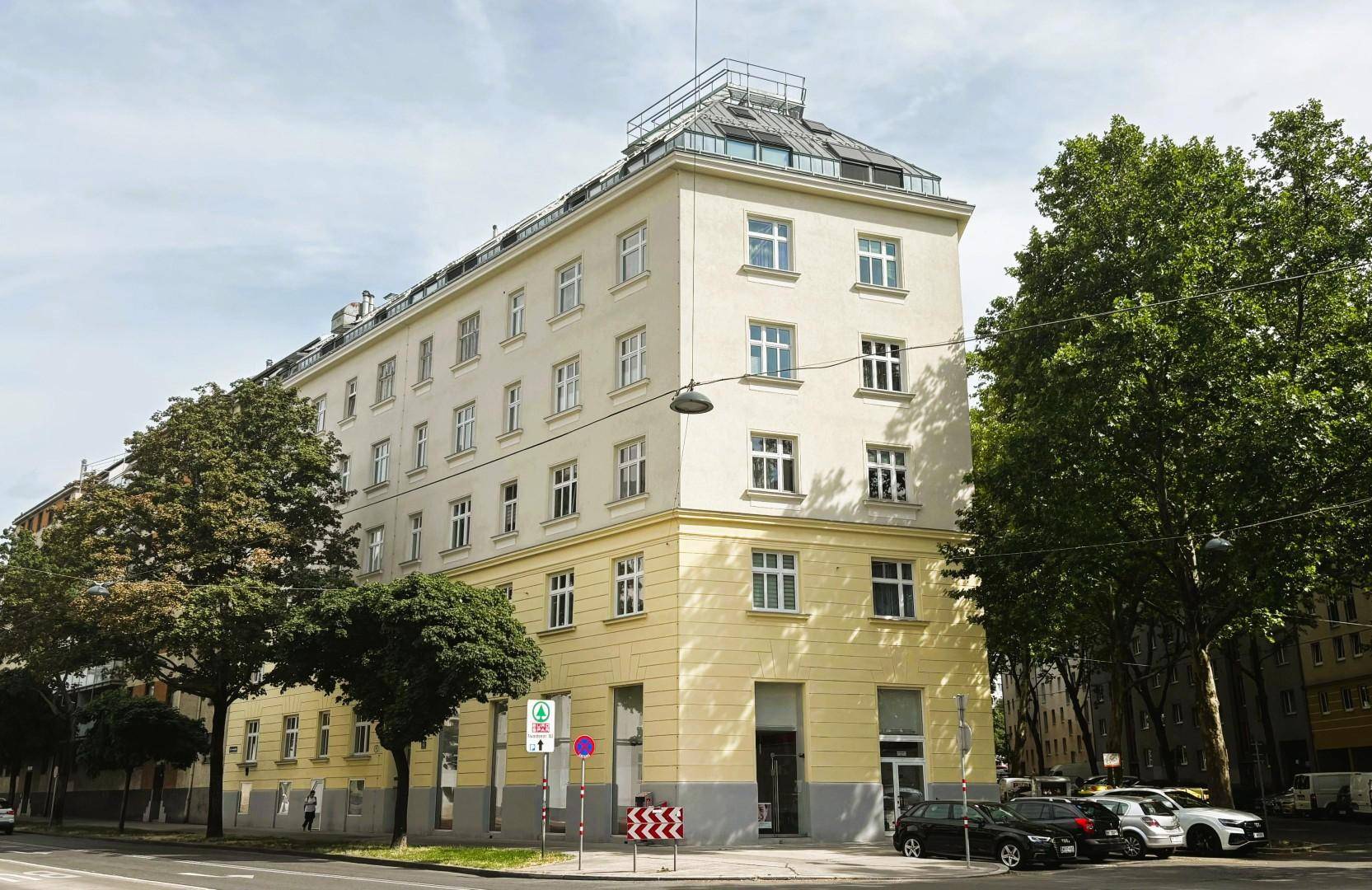 Mehrstöckiges Eckgebäude mit klassischer Fassade und vielen Fenstern an einer städtischen Straße.