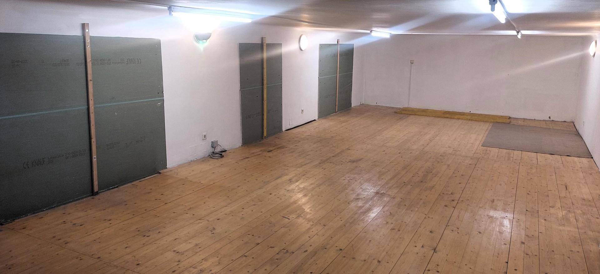 Geräumiger Lagerraum mit Holzplankenboden und provisorischen Trennwänden, gut beleuchtet.