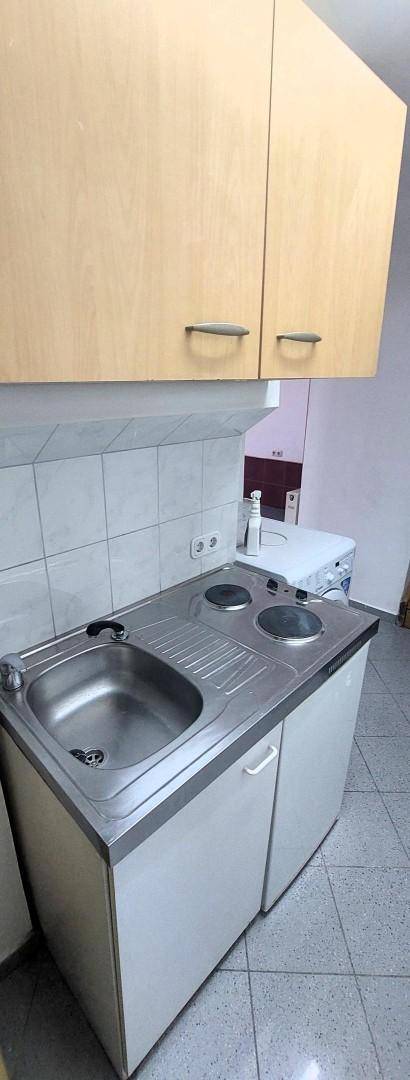 Kleine Küchenzeile mit Spüle, Kochplatten und Oberschränken, ideal für kompakte Räume.