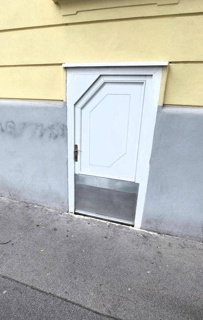 Eine kleine weiße Tür in der Fassade, die zu einem Keller oder Abstellraum führen könnte.