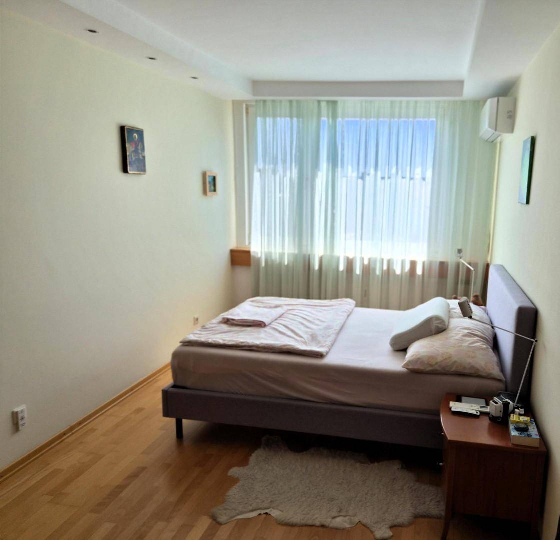 Schlafzimmer mit Doppelbett, Holzboden und großem Fenster für viel natürliches Tageslicht.