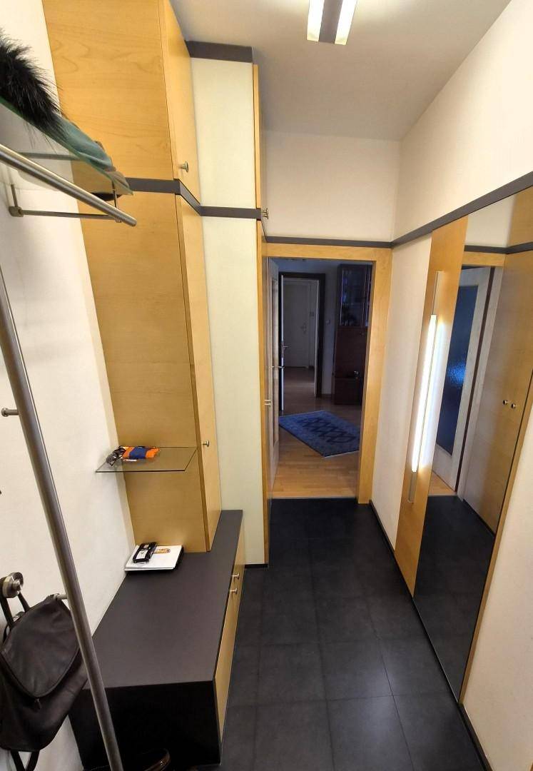 Heller Flur mit dunklen Fliesen, Garderobe und Spiegeln, der zu weiteren Räumen führt.