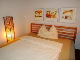 Schlafzimmer mit Doppelbett, Holzbettrahmen und dekorativen Bildern an der Wand.