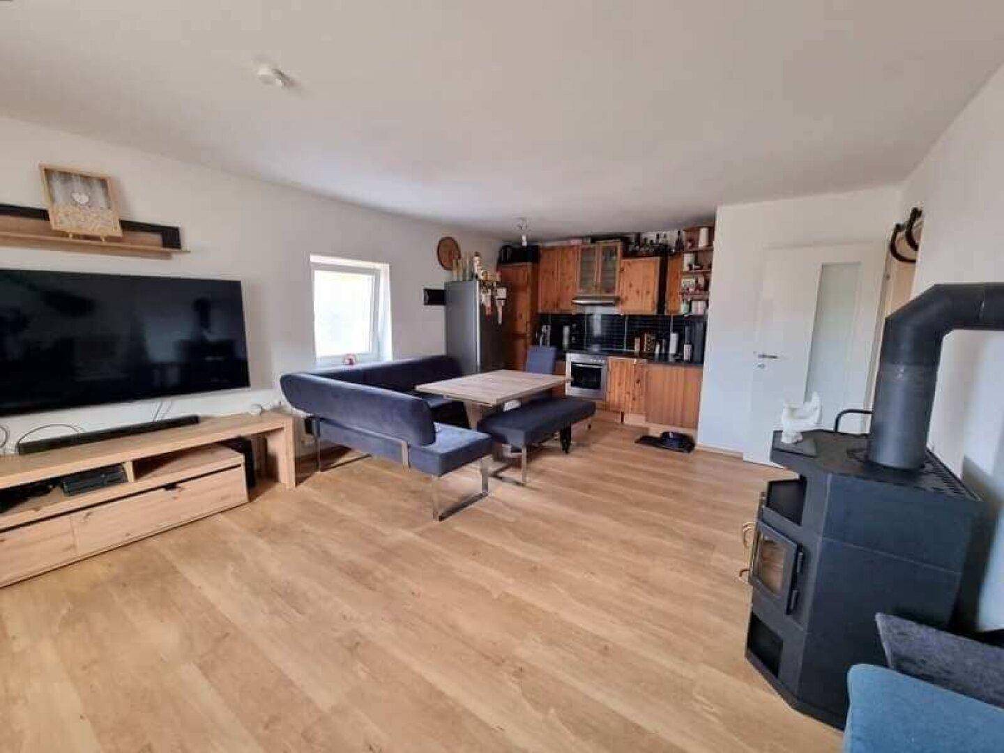 Offener Wohn-Essbereich mit Holzboden, moderner Küche und Holzofen.
