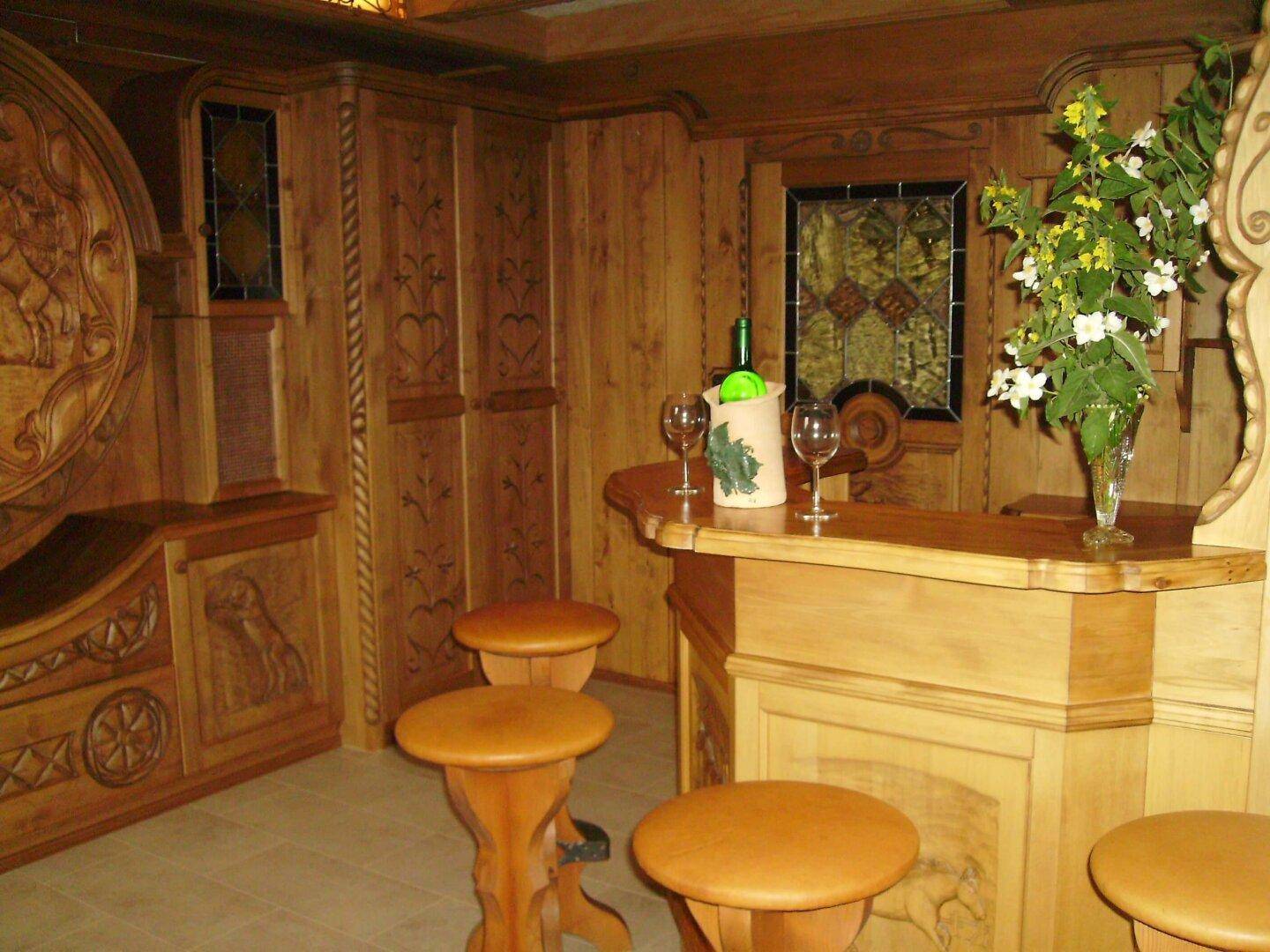 Rustikale Bar aus Holz mit geschnitzten Details und Hockern, ideal für gesellige Abende.
