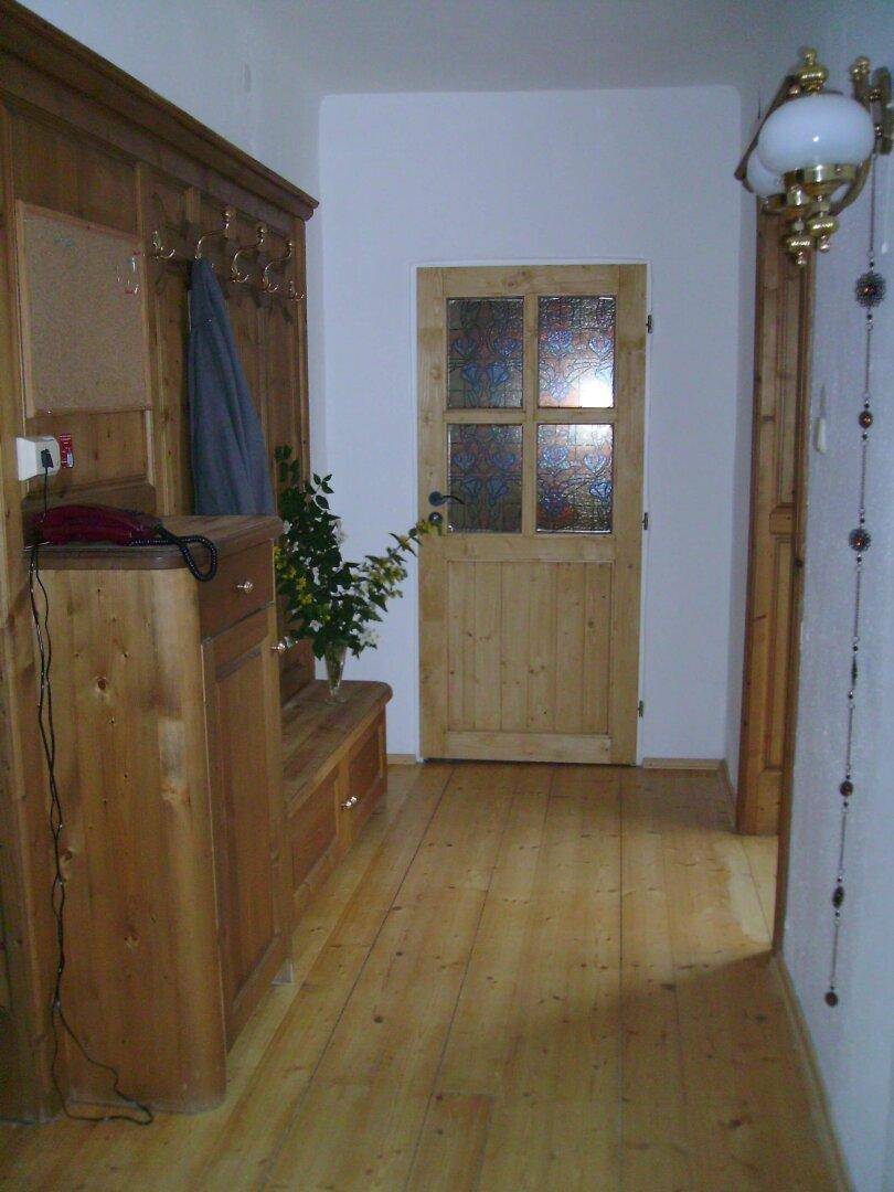 Flur mit rustikalen Holzmöbeln und Garderobe, sowie einer Holztür mit Glaseinsätzen.