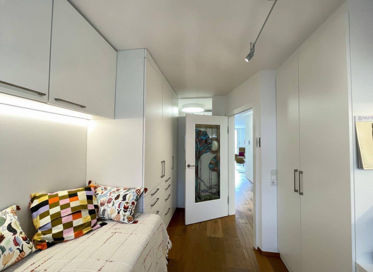 Schlafzimmer mit durchdachten Einbauschränken und Holzboden, bietet viel Stauraum und eine helle Atmosphäre.