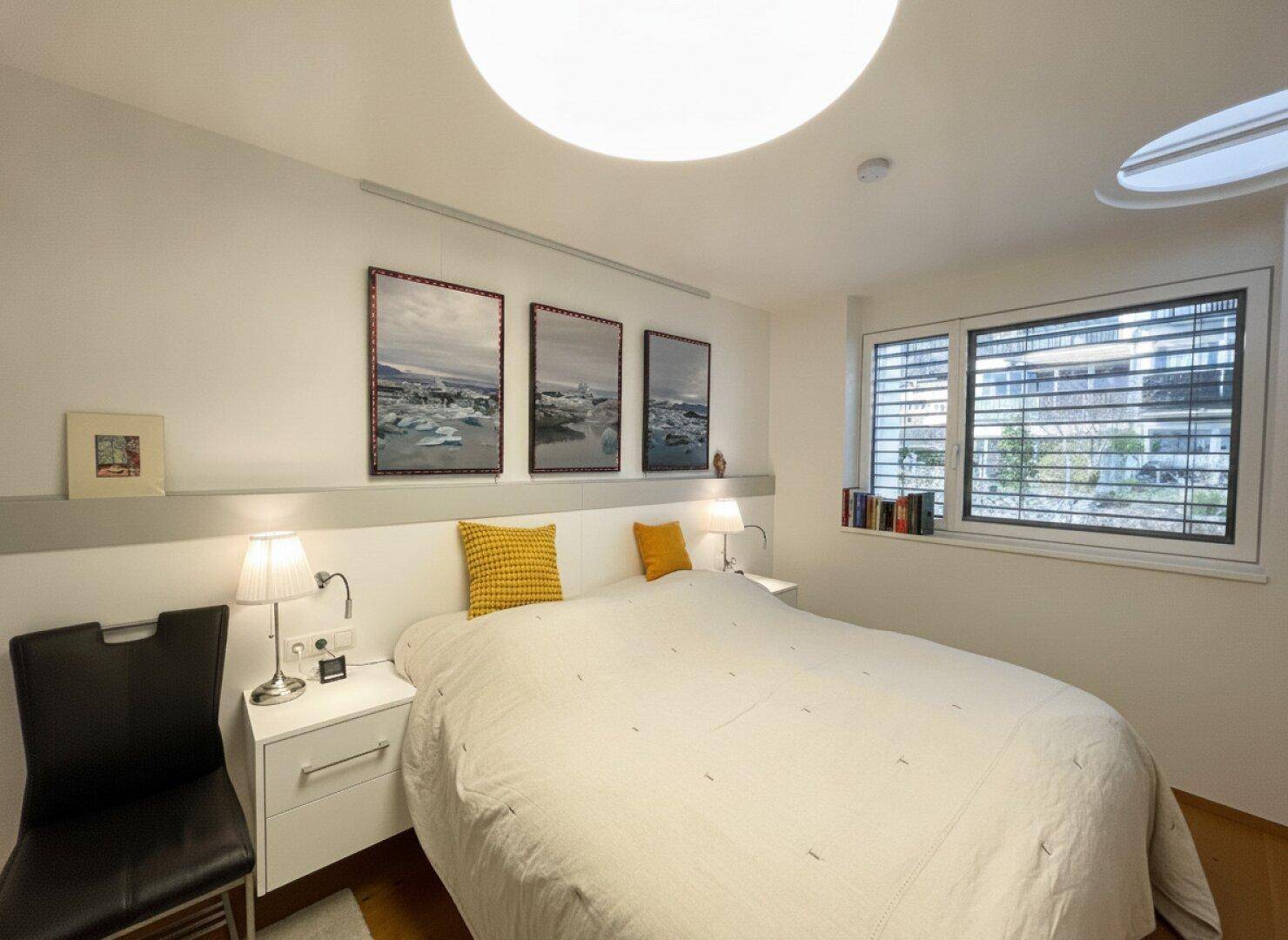 Gemütliches Schlafzimmer mit Doppelbett, Nachttischen und großem Fenster, sorgt für angenehmes Tageslicht.