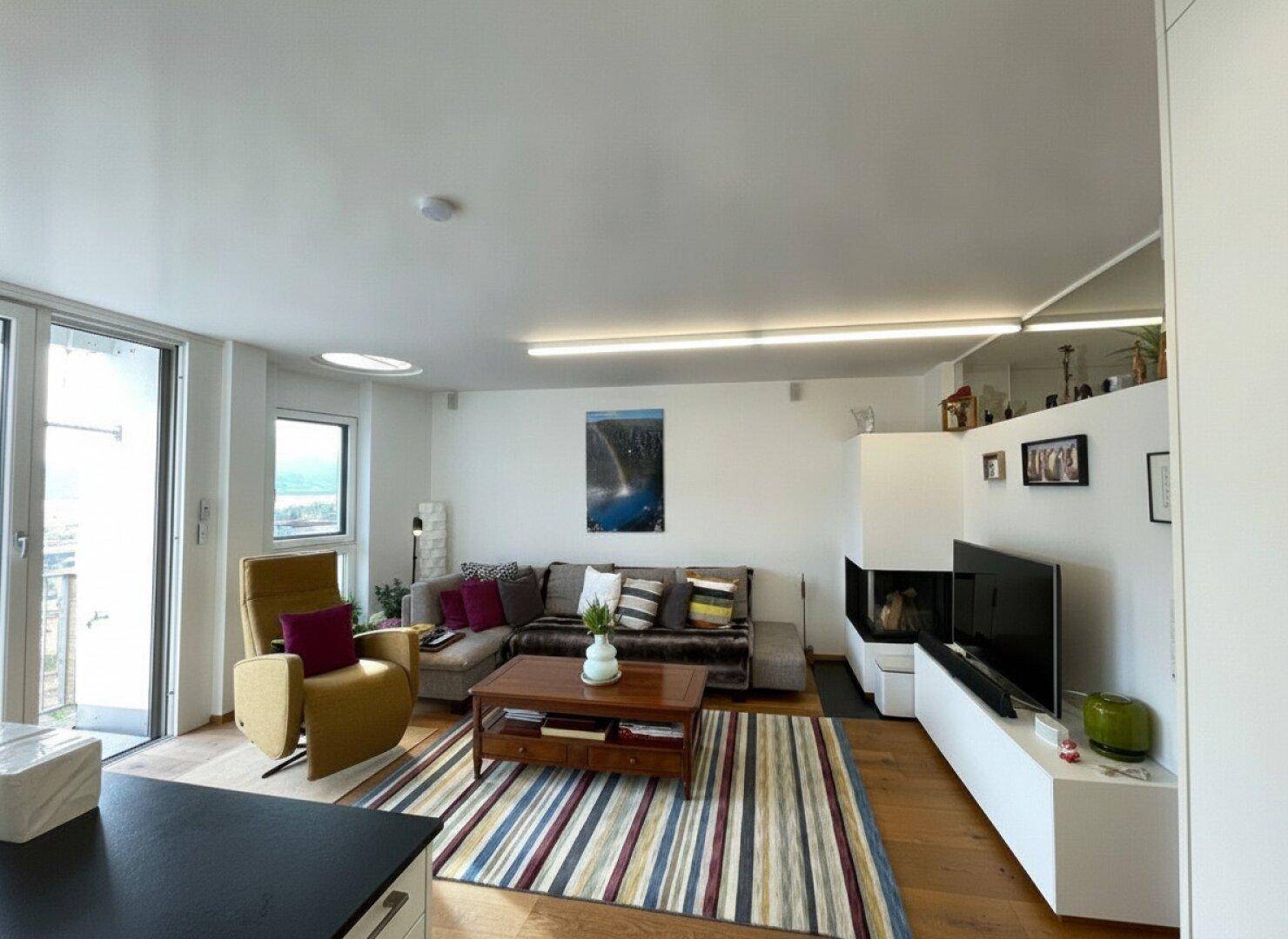 Helles Wohnzimmer mit gemütlichem Sofa, modernem Kamin und Holzboden, ideal zum Entspannen.