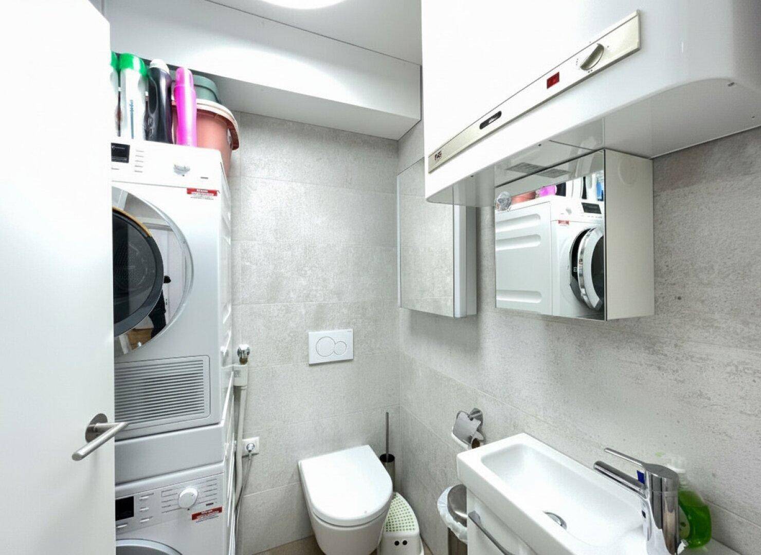 Kleines Gäste-WC mit Toilette, Waschbecken und integrierter Waschmaschine, praktisch und platzsparend.