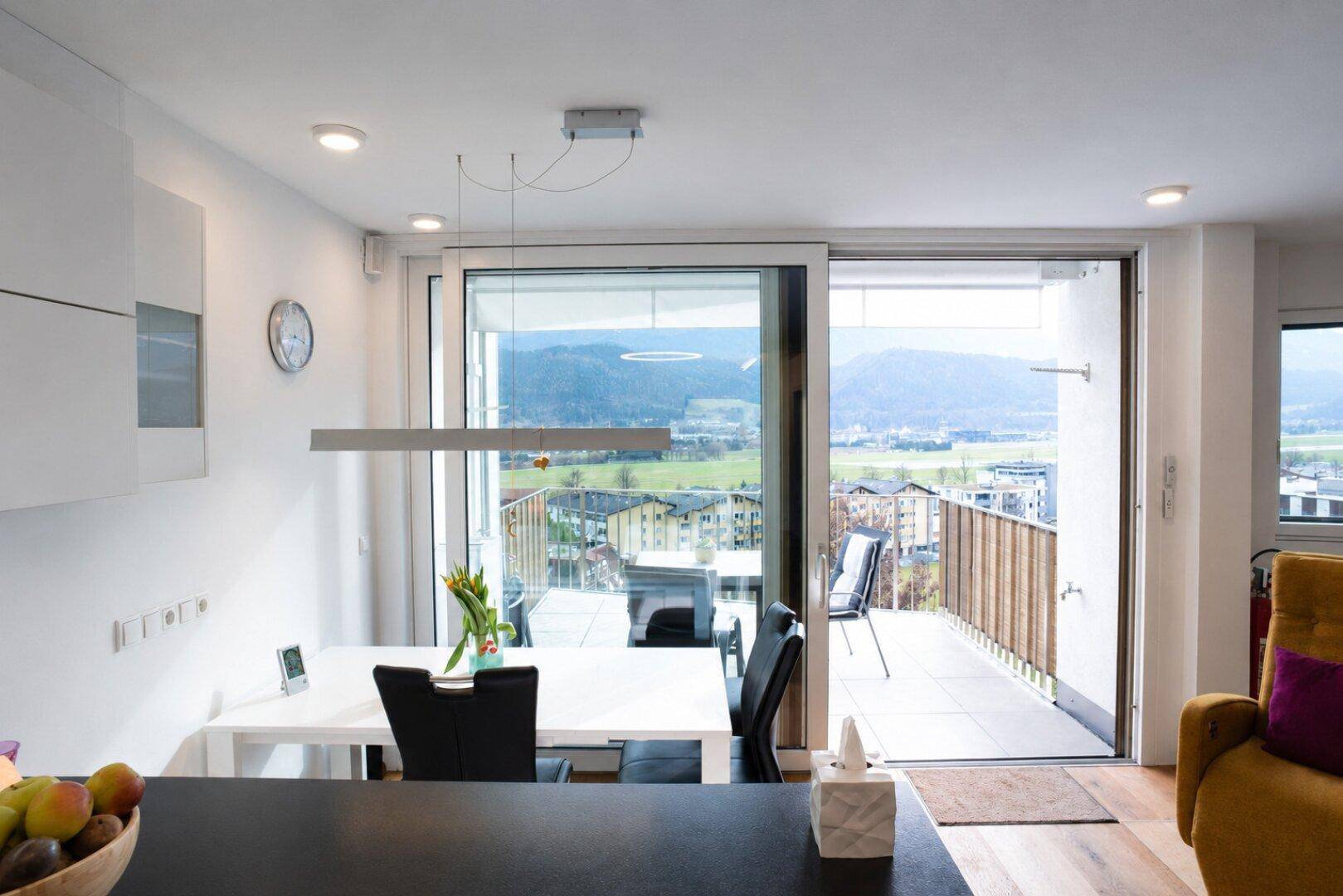 Heller Essbereich mit modernem Esstisch und Zugang zum Balkon, bietet einen schönen Bergblick.