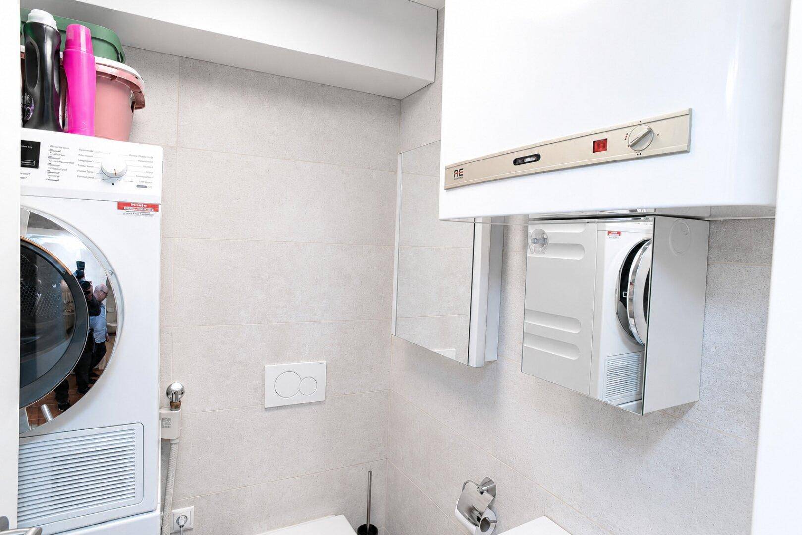 Praktischer Hauswirtschaftsraum mit Waschmaschine, Trockner und Warmwasserbereiter, funktional eingerichtet.