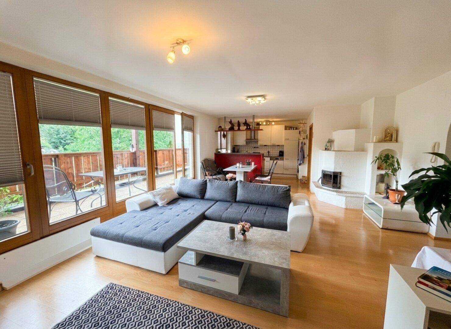 Geräumiger Wohnbereich mit Ecksofa, Kamin und offener Küche im Hintergrund.