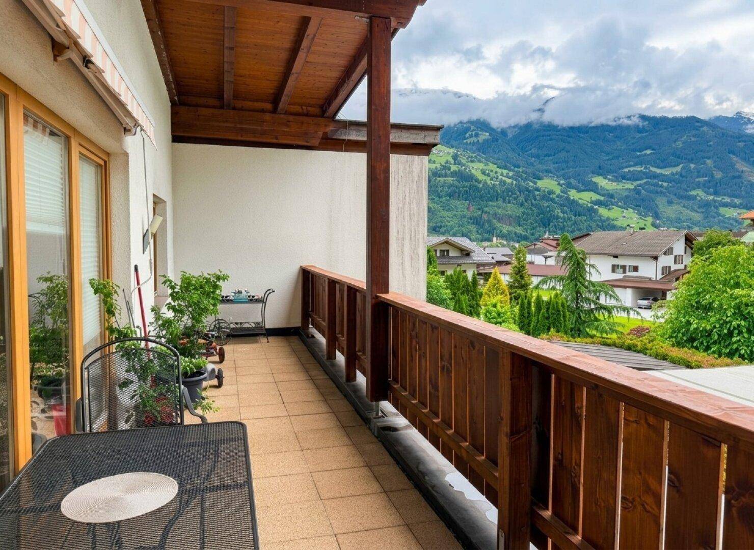 Geräumiger Balkon mit Holzboden, Sitzgelegenheiten und beeindruckendem Bergblick.