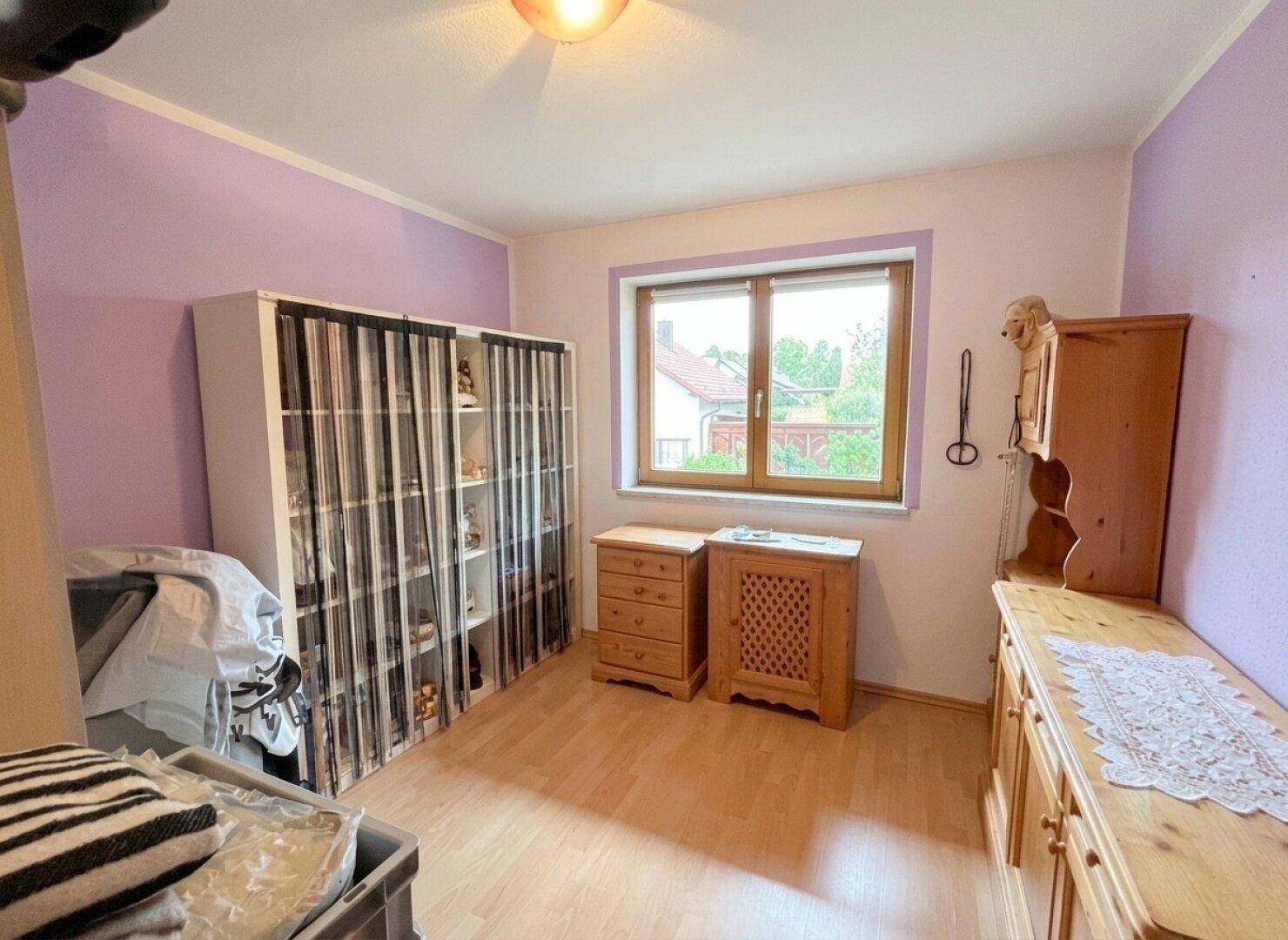 Schlafzimmer mit Laminatboden, Schrank und Fenster mit Blick auf die Nachbarschaft.