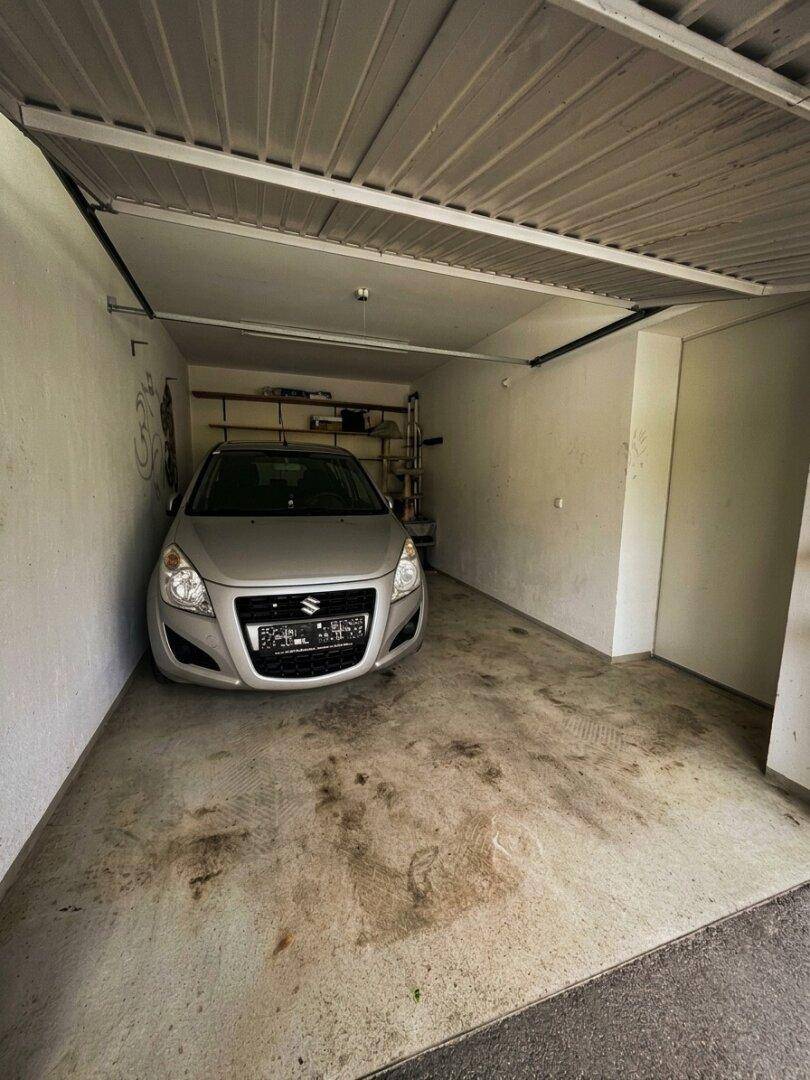 Einzelgarage mit Betonboden und einem geparkten Auto.