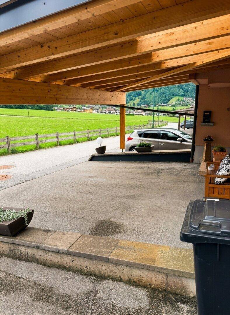 Überdachter Stellplatz (Carport) mit Holzbalken und Blick auf die grüne Landschaft.