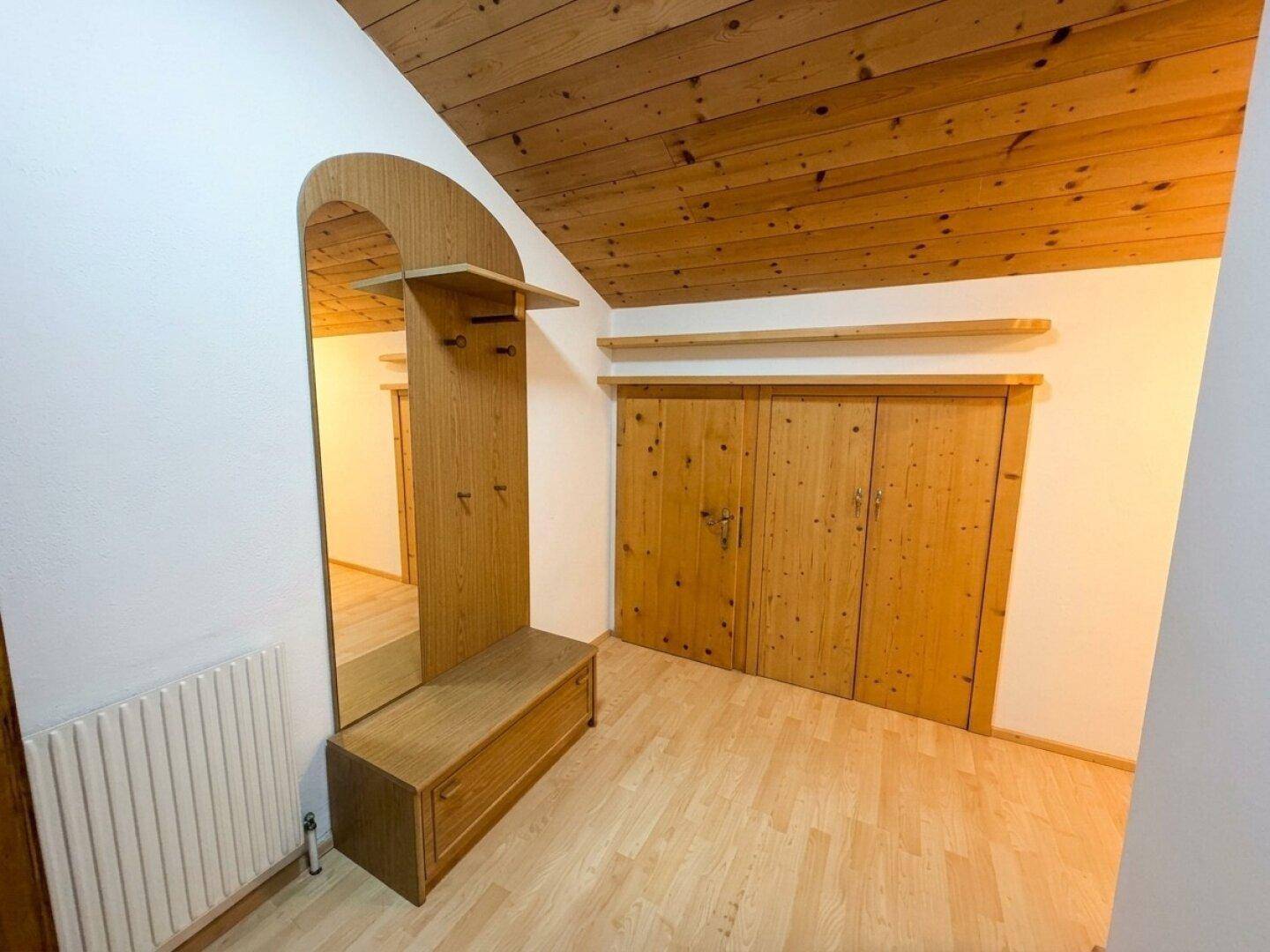 Gemütlicher Flur mit Holzdecke, Laminatboden und einem Garderobenschrank mit Spiegel.