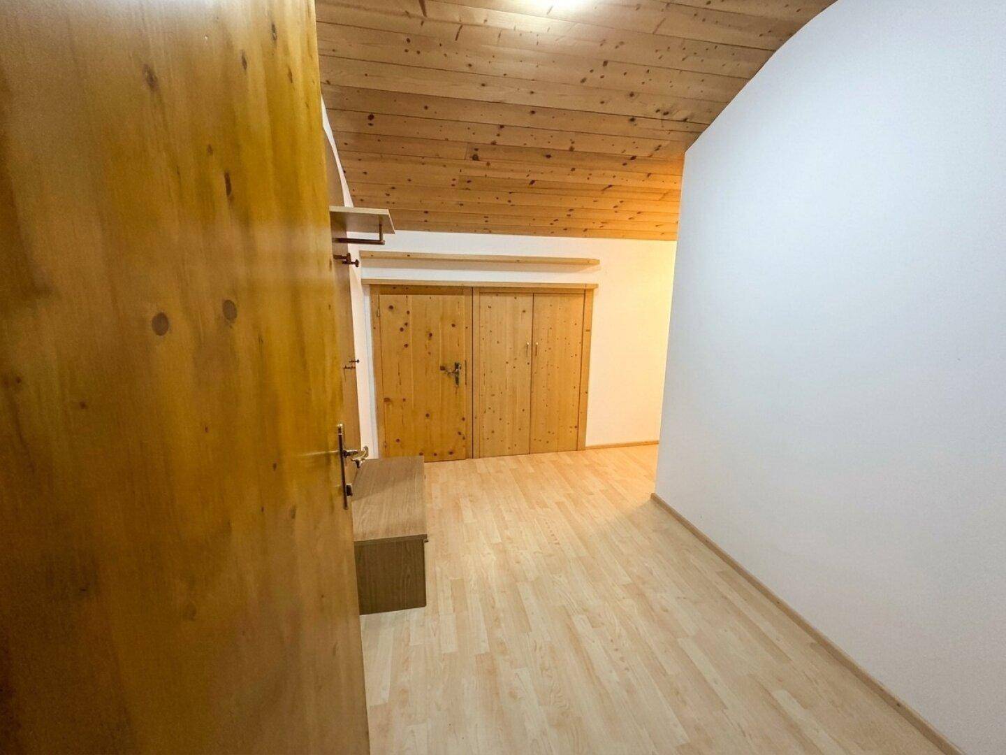 Heller Flur mit Holzbalkendecke, Laminatboden und integrierten Holzschränken.
