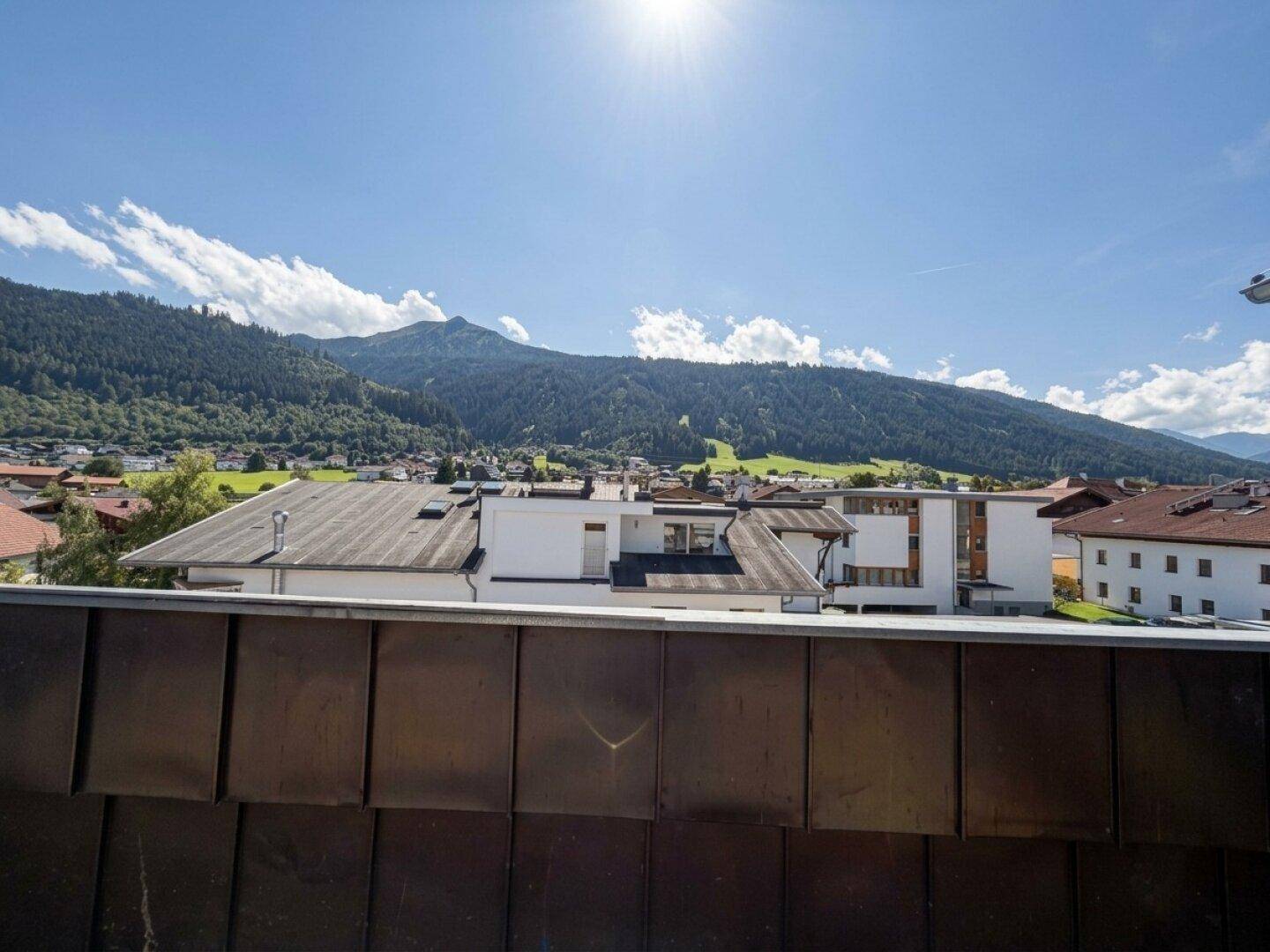 Panoramablick über die Dächer der Stadt auf die umliegende Berglandschaft an einem sonnigen Tag.