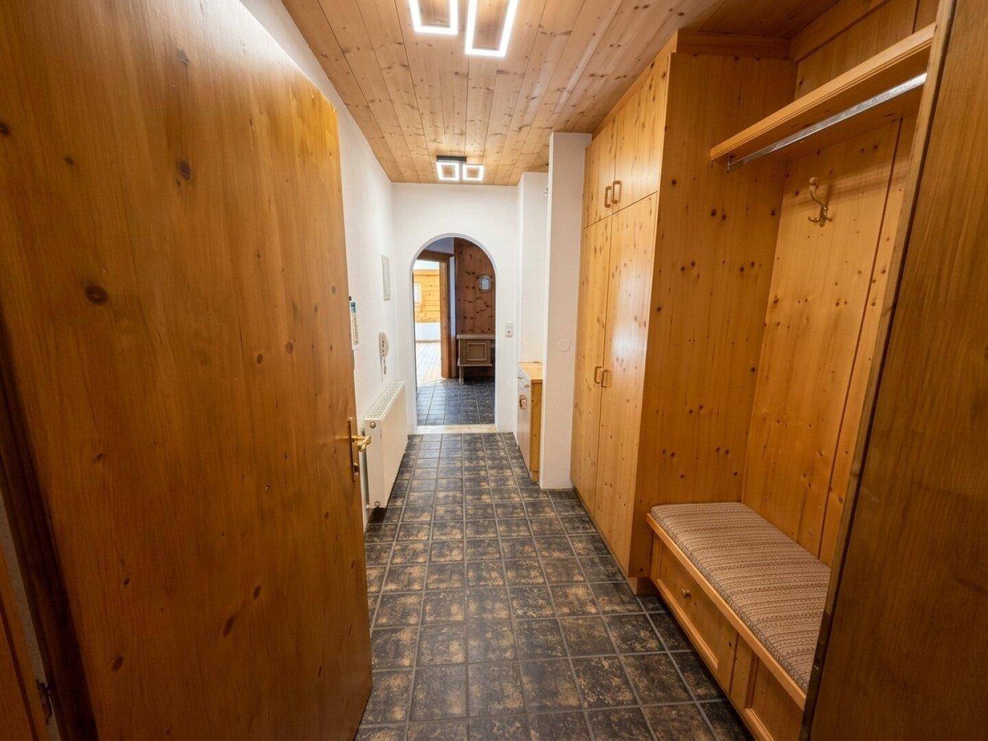 Traditioneller Flur mit Holzvertäfelung, Einbauschränken und dunklem Fliesenboden.