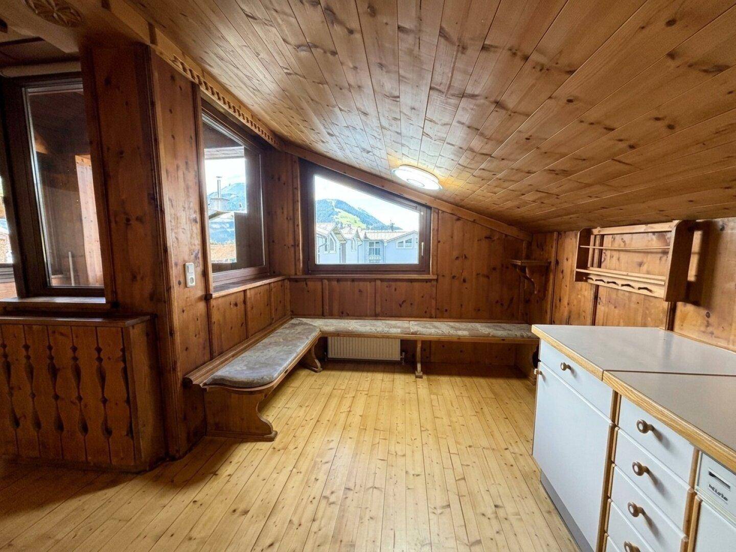 Küche im Dachgeschoss mit Holzvertäfelung, schrägen Decken und integrierter Sitzbank.