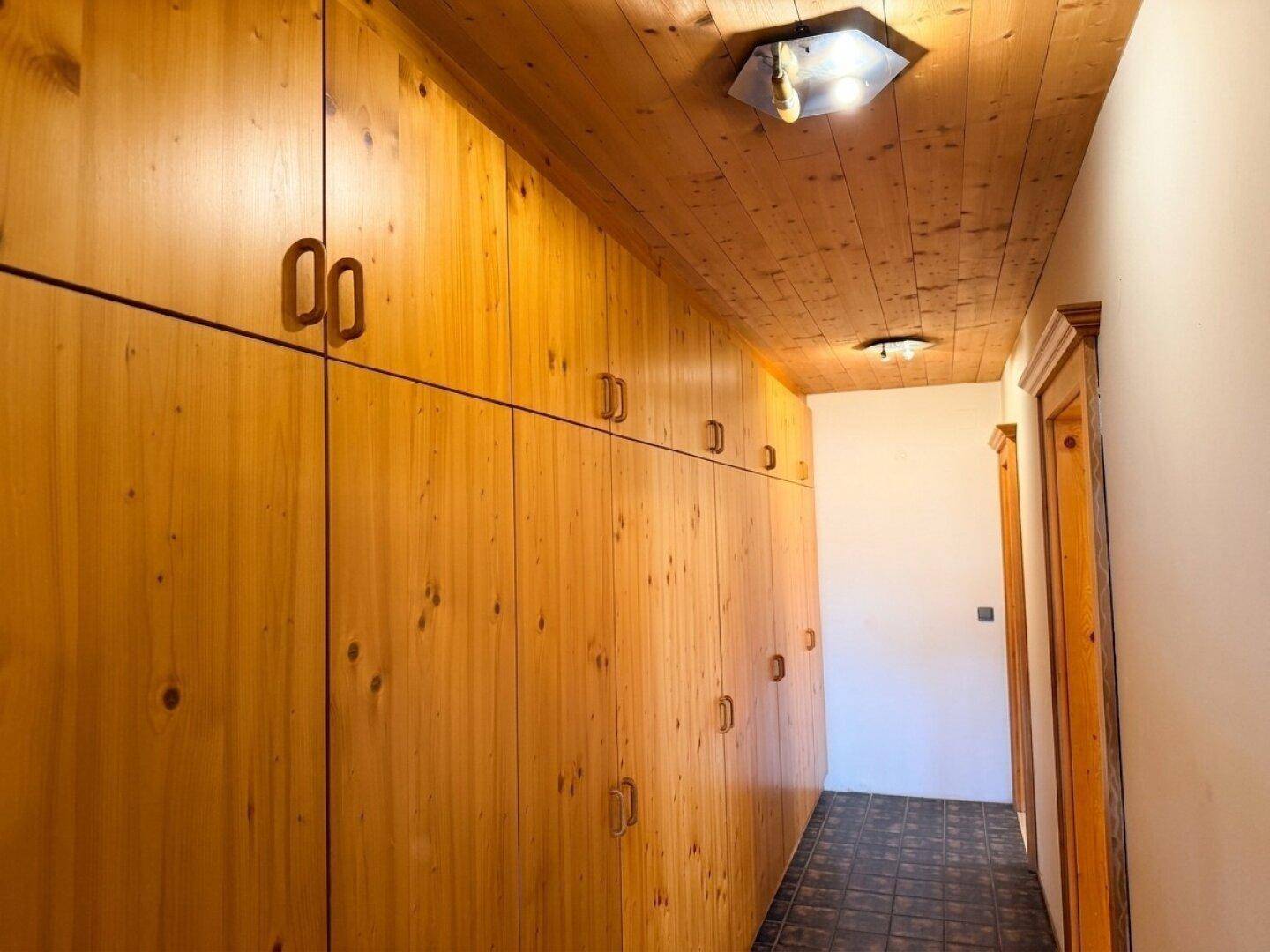 Langer Flur mit durchgehenden Holzschränken und passender Holzdecke im traditionellen Stil.