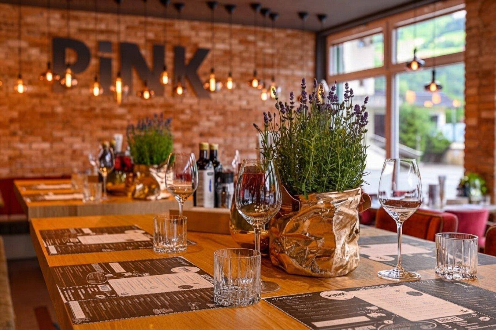 Nahaufnahme eines gedeckten Tisches in einem Restaurant mit Weingläsern, Besteck und einer Lavendelpflanze als Dekoration.