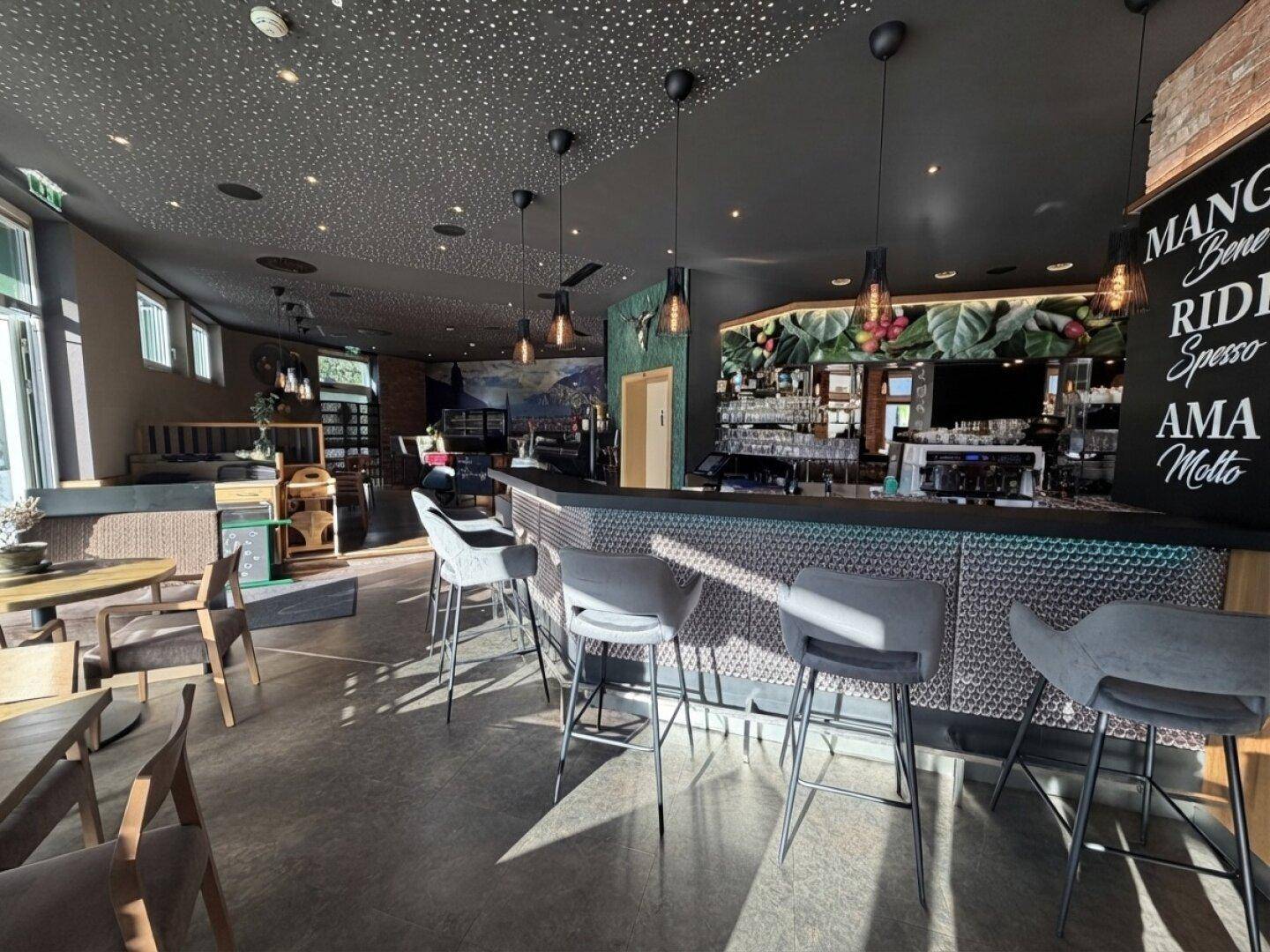Elegante Bar mit modernen Barhockern, einer strukturierten Theke und einer tropischen Wanddekoration im Hintergrund.