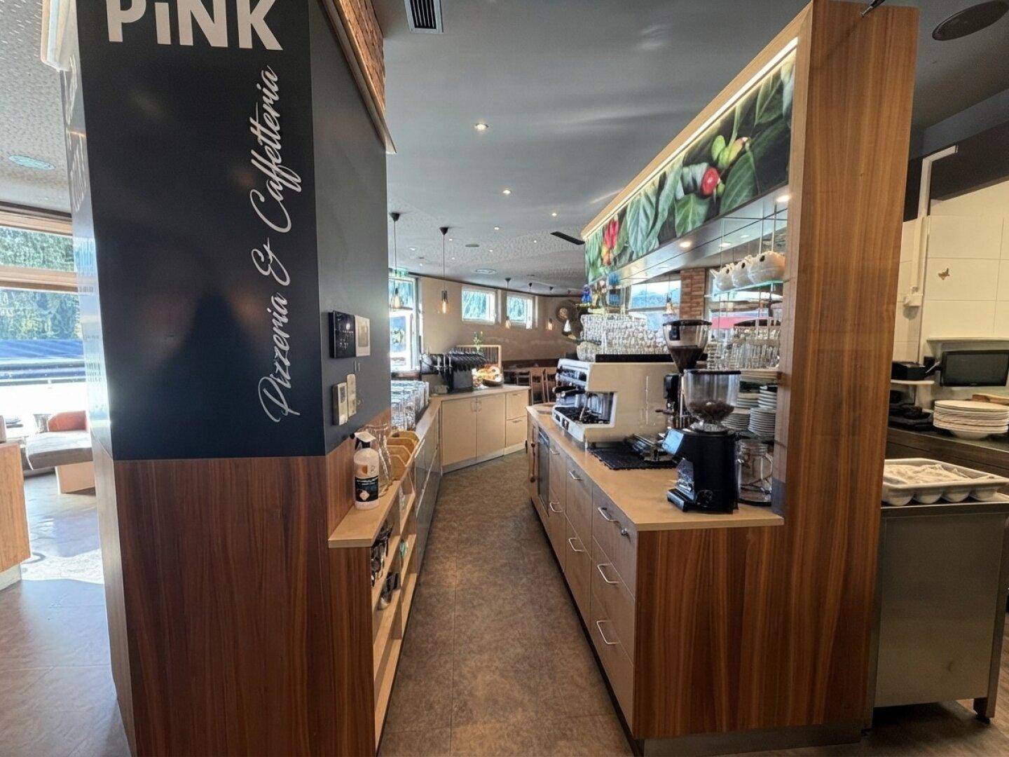 Professionelle Küche mit Holzelementen, modernen Geräten und einer Kaffeestation für den Restaurantbetrieb.
