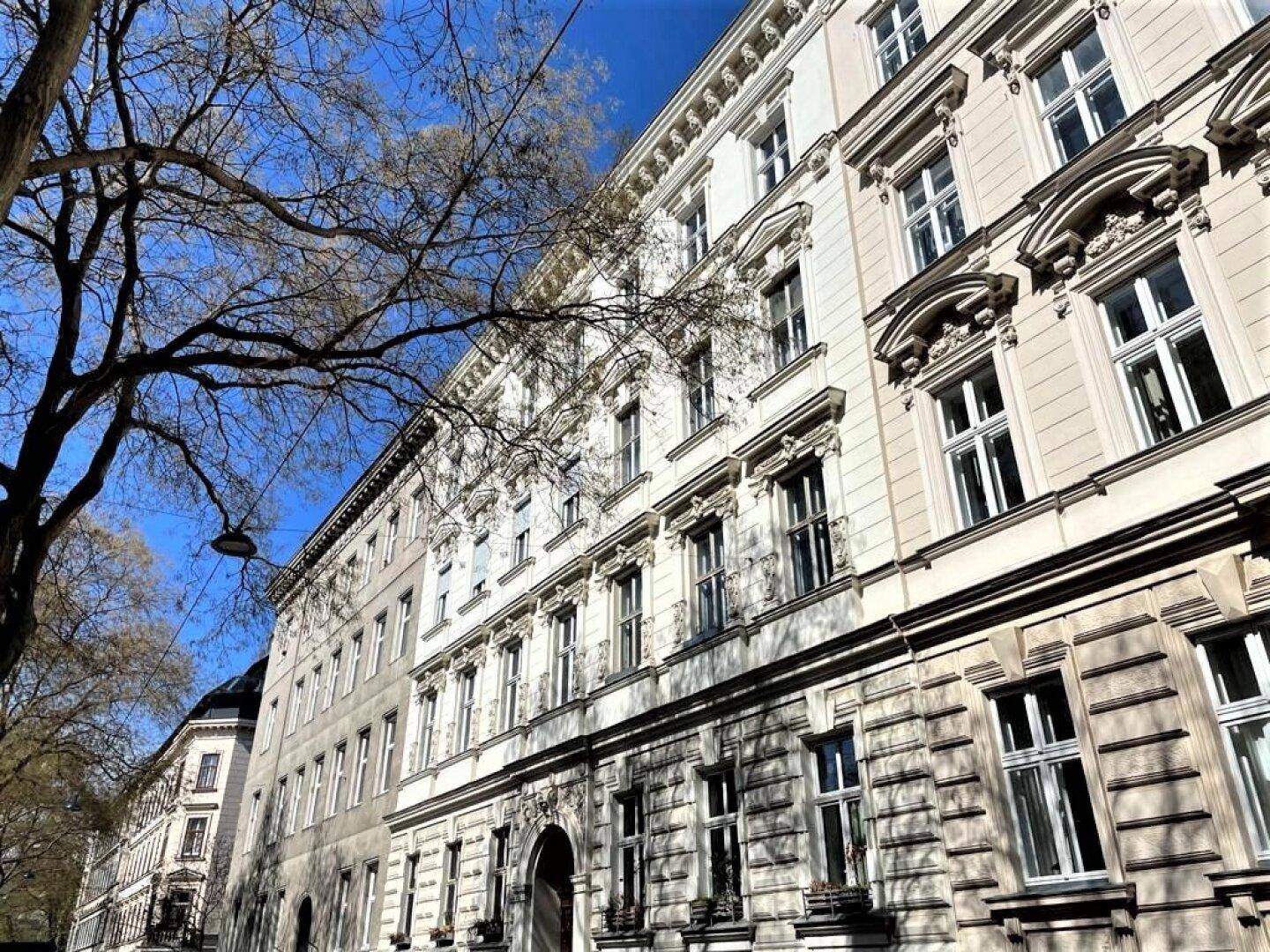 Historisches Gebäude mit klassischer Architektur und vielen Fenstern unter strahlend blauem Himmel.