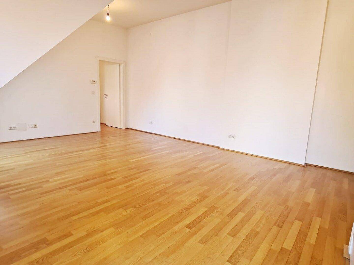 Heller Wohnraum mit Holzboden und weiß gestrichenen Wänden, bereit zum Einzug.