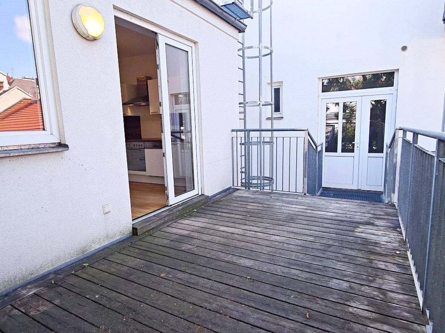 Geräumiger Balkon mit Holzboden und Blick auf die Umgebung, mit Zugang zur Küche.