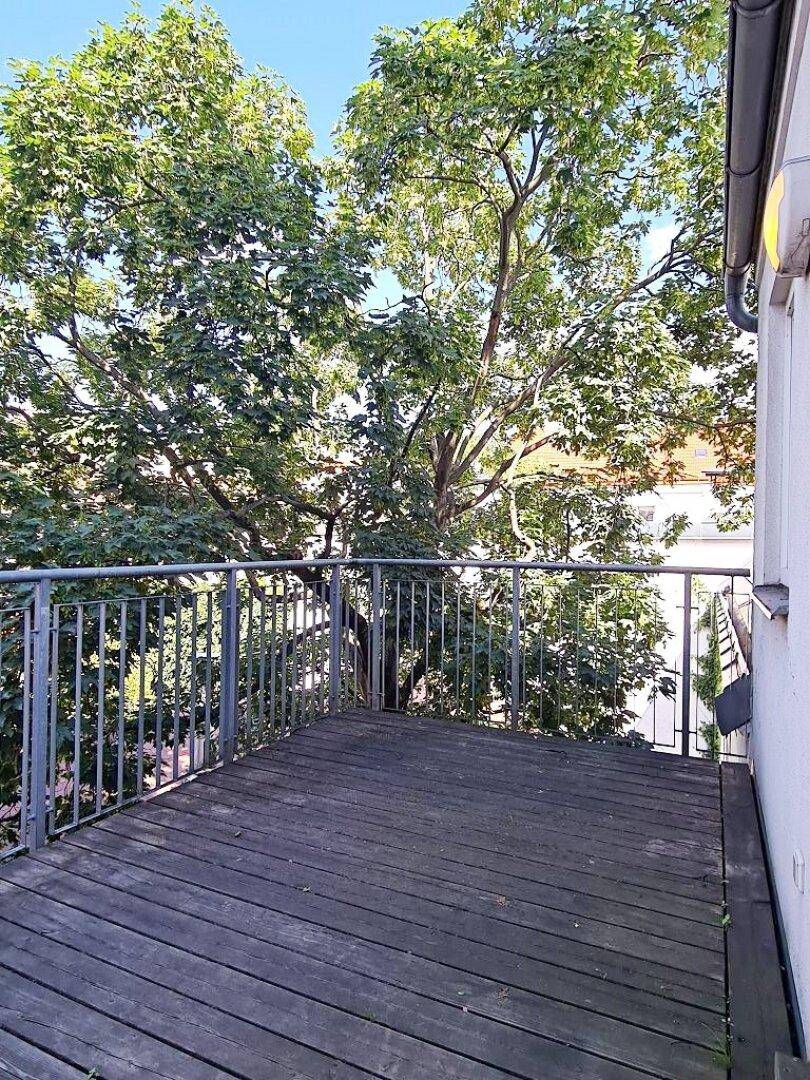 Balkon mit Holzboden und üppigem Grünblick, ideal für ruhige Stunden im Freien.