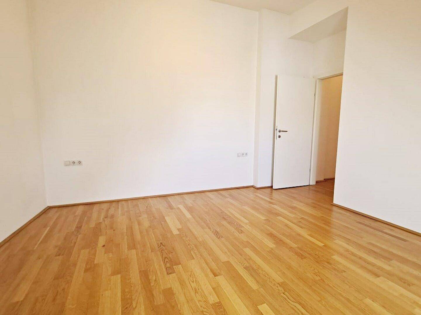 Helles Zimmer mit Holzboden und weißen Wänden, bietet viel Platz und Gestaltungsmöglichkeiten.