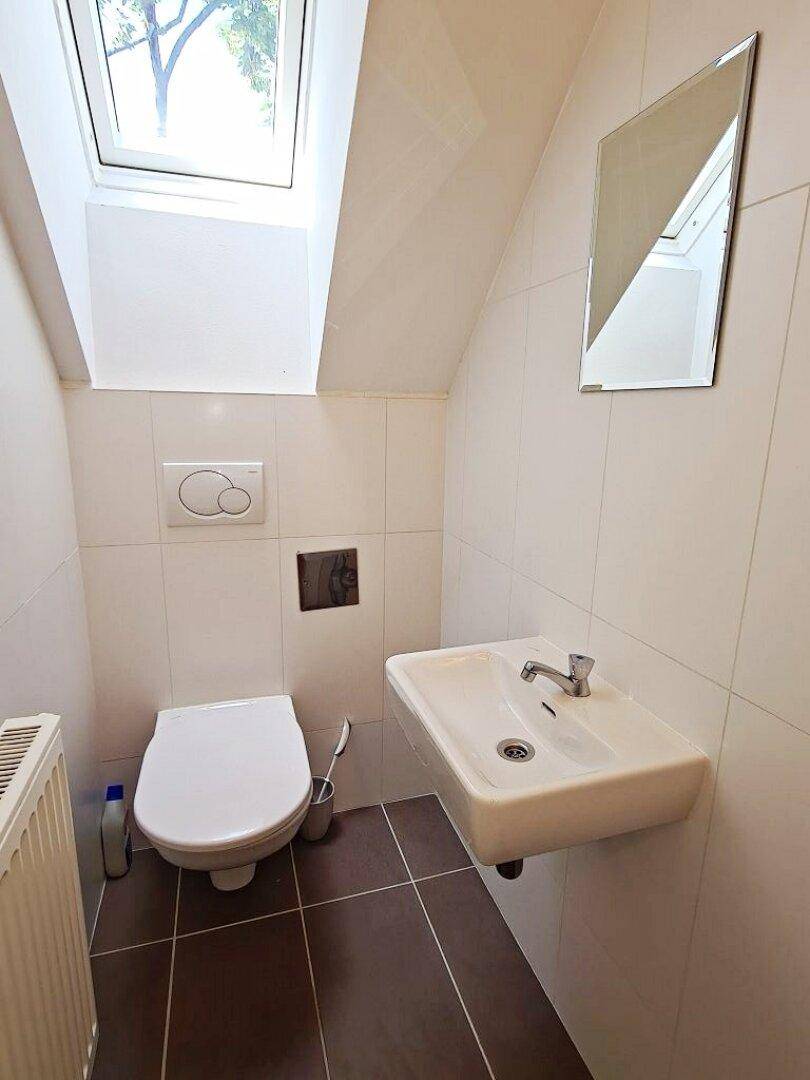 Helles WC mit Dachfenster, wandhängendem WC und modernem Waschbecken.
