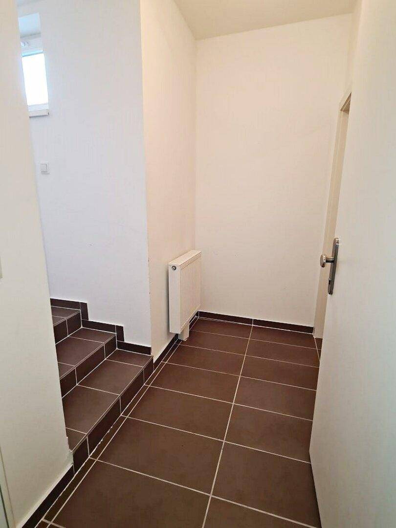 Eingangsbereich mit Fliesenboden, Treppe und Heizkörper, führt zu den oberen Etagen.