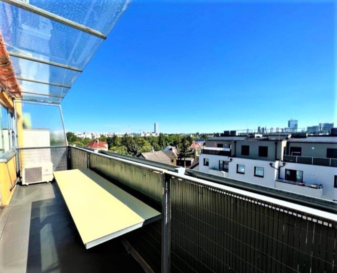 Überdachter Balkon mit Blick auf die Stadt und angrenzende Wohngebäude.