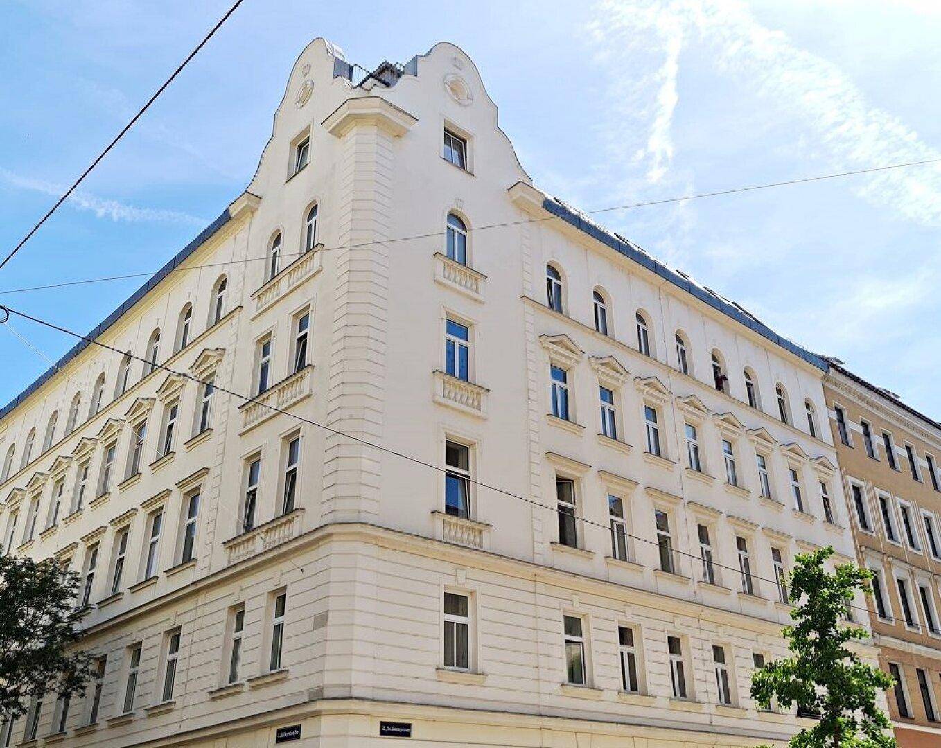 Eckansicht eines historischen Gebäudes mit klassischer Architektur und vielen Fenstern unter klarem Himmel.