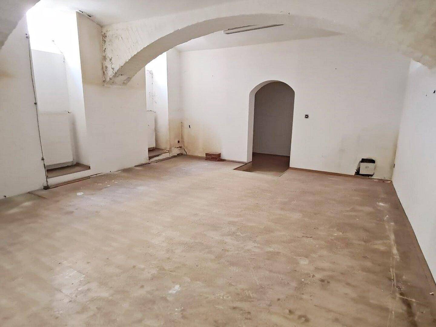 Unfertiger Innenraum mit Gewölbedecken und einem Durchgang, der auf Renovierungsbedarf hinweist.