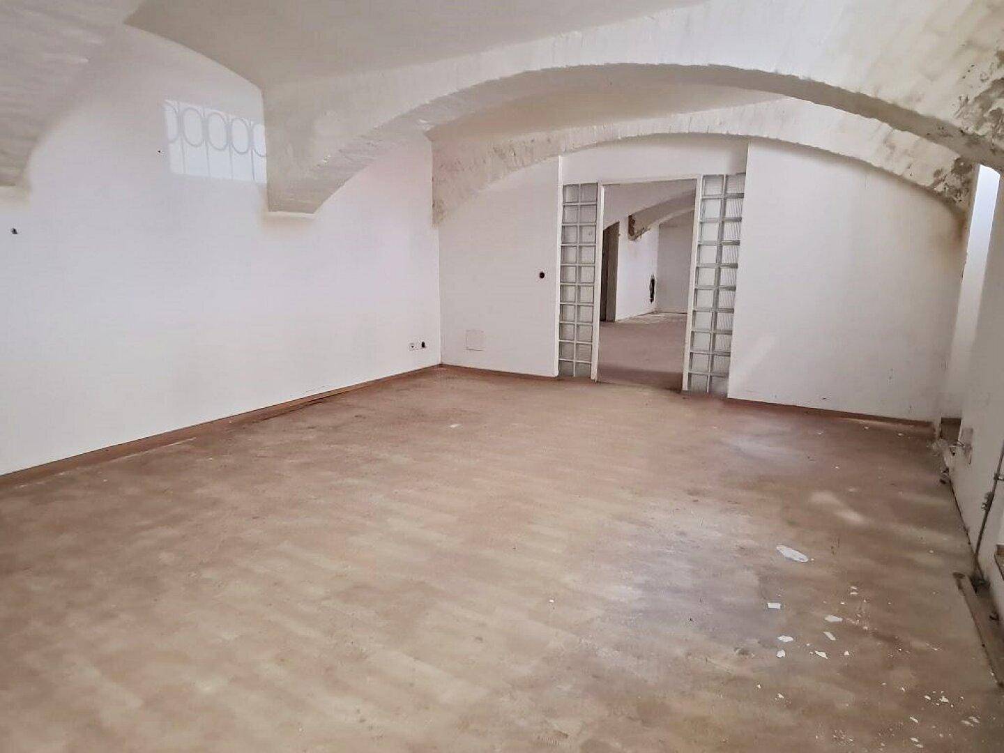Geräumiger Innenraum mit Gewölbedecken und Glasbausteinen, der auf eine bevorstehende Renovierung wartet.