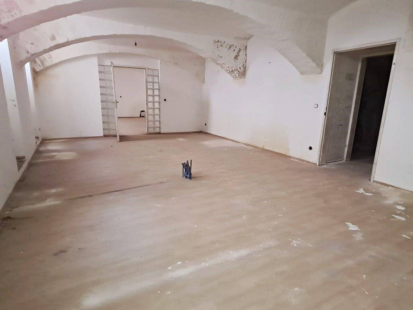 Großer Innenraum mit Gewölbedecken, Glasbausteinen und offener Tür, der renoviert werden muss.