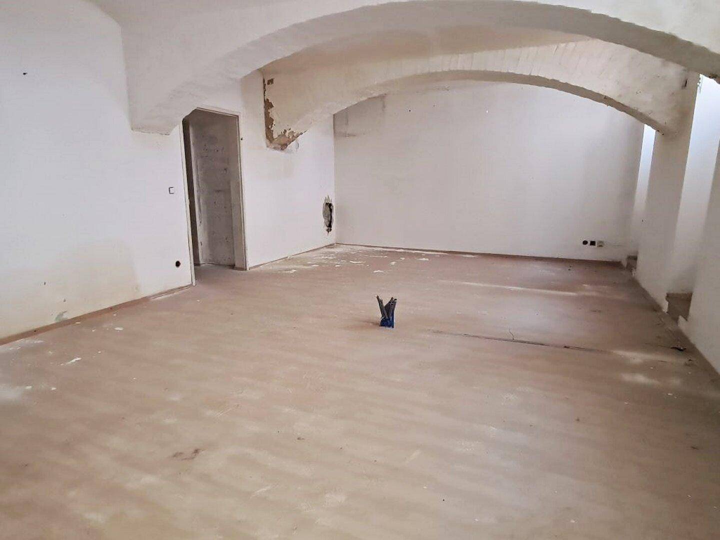 Unfertiger Innenraum mit Gewölbedecken und einem offenen Durchgang, der auf eine Renovierung wartet.