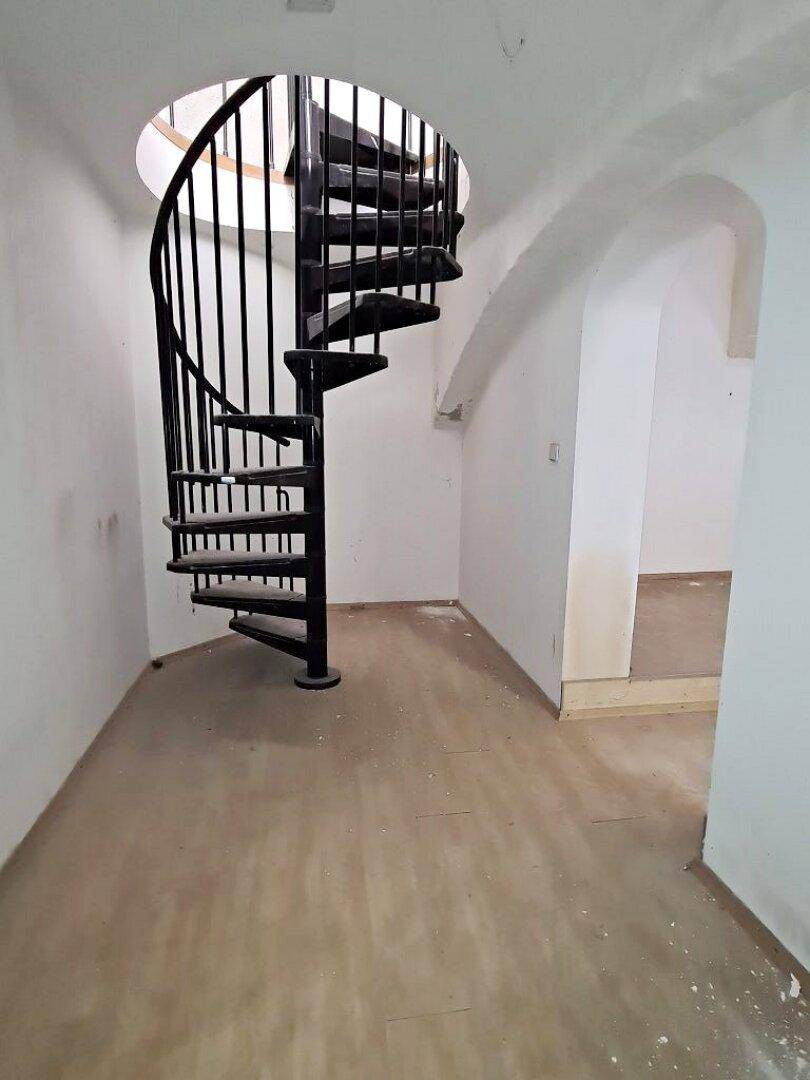 Innenraum mit einer schwarzen Wendeltreppe und Gewölbedecke, der auf Fertigstellung wartet.